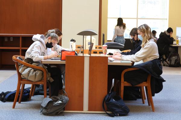Students writing around a table in the library