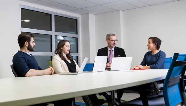 Students talking with prof at a table