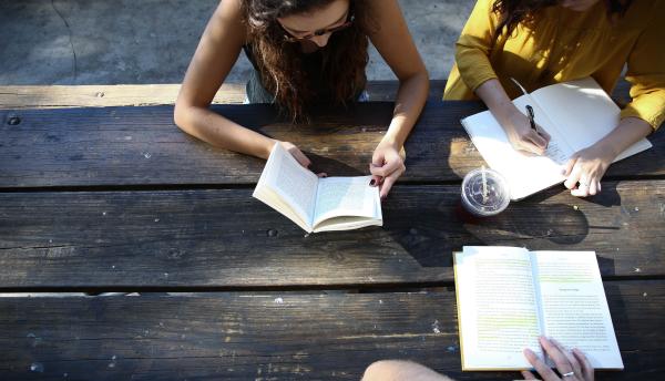 Three people working at a picnic table