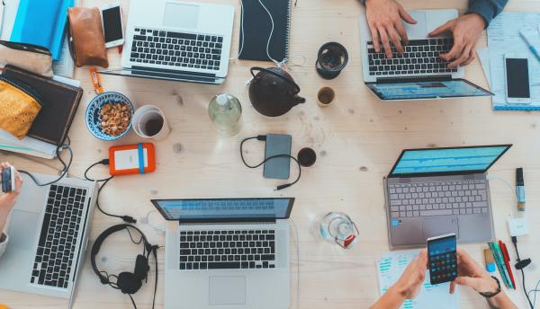 Overhead shot of laptops on a desk with students studying.