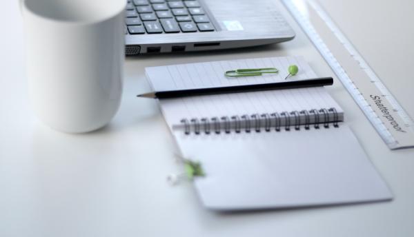 Notebook, mug, pencil and laptop on a table