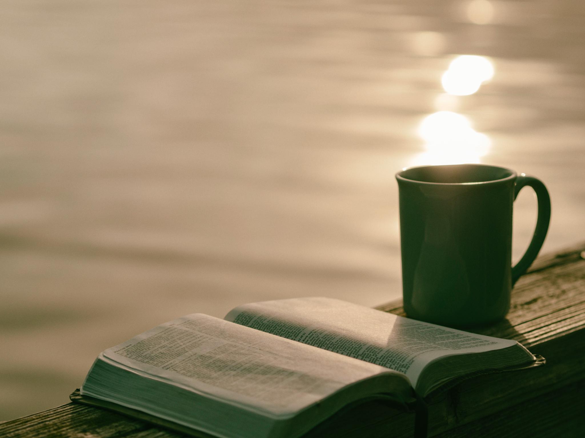 coffee cup and notepad next to a sunny lake