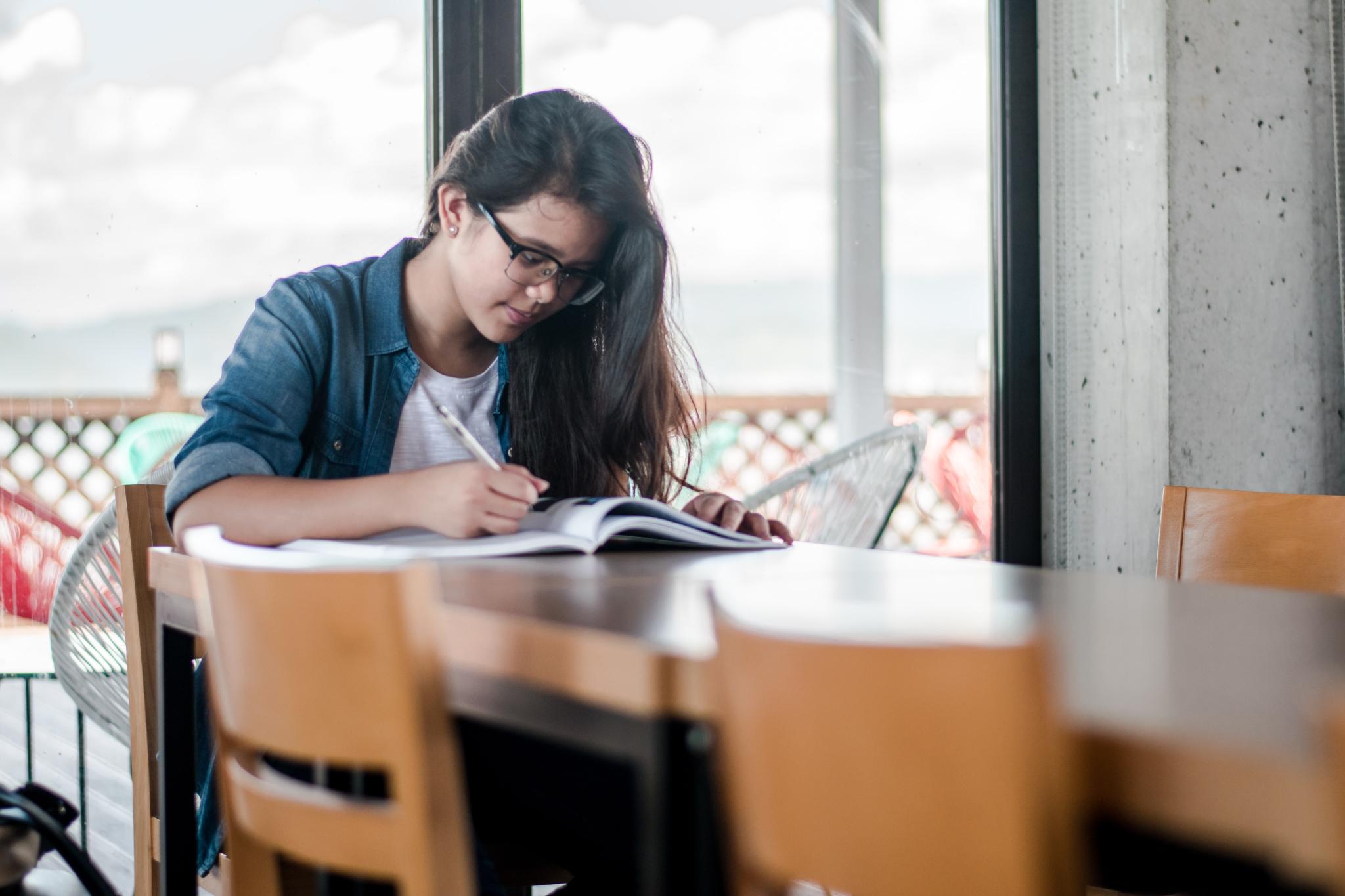 student takes notes at a table