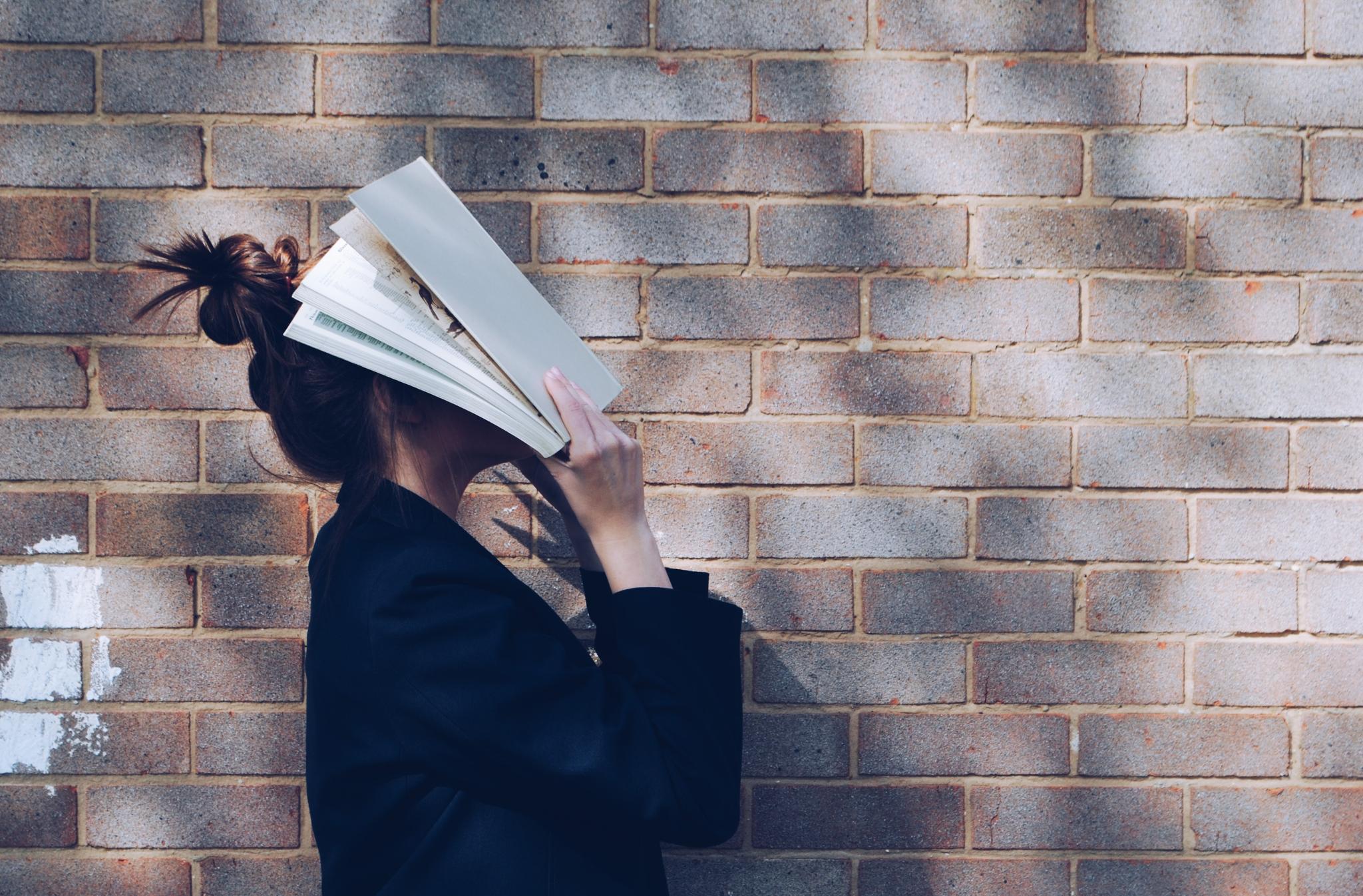 student hides face in book