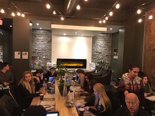 Students at long tables in warmly lit coffee shop