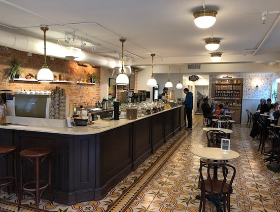 Long bar and small round tables in coffee shop with traditional tiled flooring