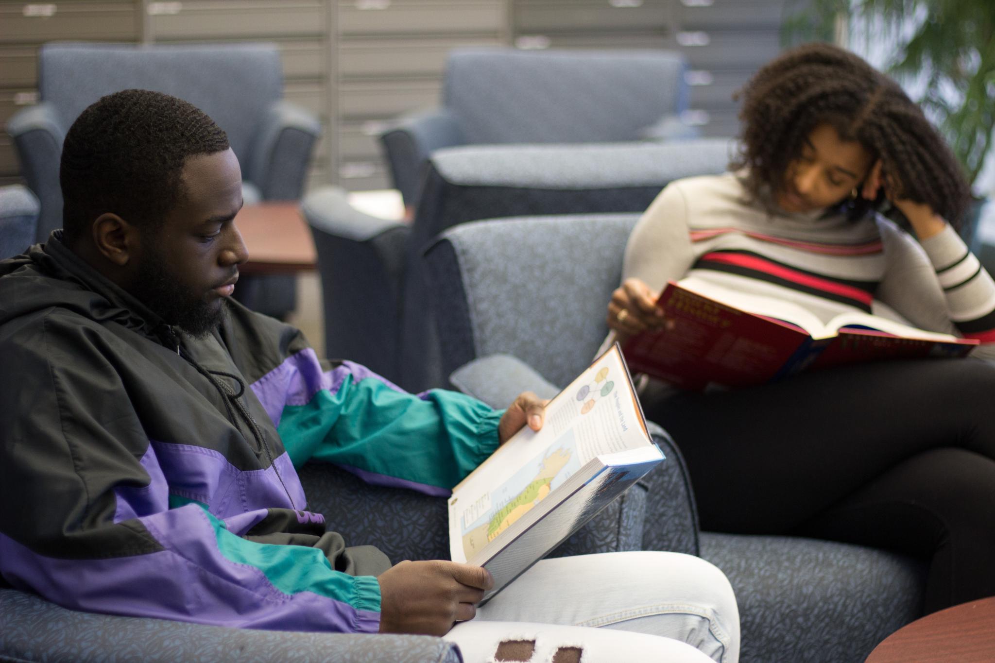 two students sit reading books